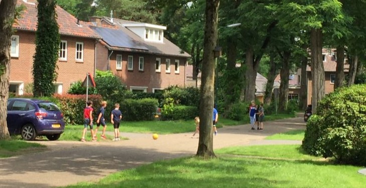 Voetballende kinderen in een groene straat in Maarn